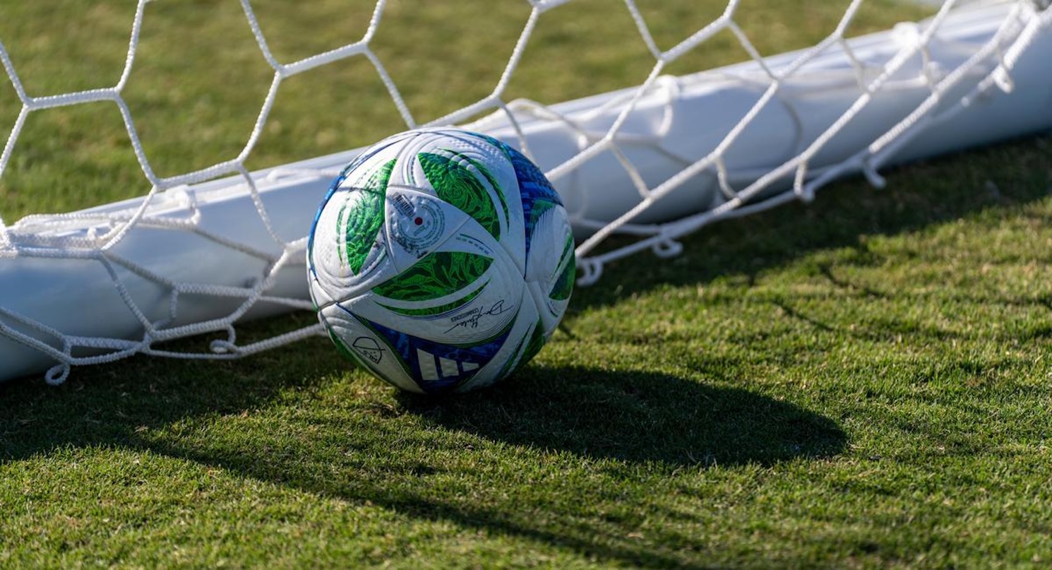 Blue green and white soccer ball in net on field